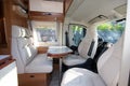 Campervan modern wooden table and white seat interior in luxury motor home on rv vanlife concept Royalty Free Stock Photo