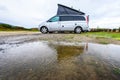 Campervan or motorhome camping on rainy day with rain puddles