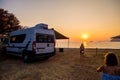 Campervan is parked on the beach at sunset