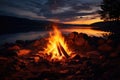 A campfire burns brightly as darkness falls, casting a warm glow by the waters edge, Wonderful evening atmospheric background of Royalty Free Stock Photo