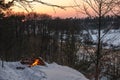 Campfire burns in the snow in the forest hill, on a background of snow covered trees and mountains campfire burning in cold winter