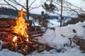 Campfire burns in the snow in the forest hill, on a background of snow covered trees and mountains campfire burning in cold winter