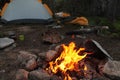 Campfire in campsite with tent set up and other camp necessities in the adventurous mountains