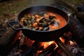 campfire with cioppino pot simmering over open flame
