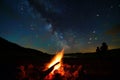 campfire foreground with silhouettes watching meteors