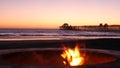 Campfire pit in California USA. Camp fire on twilight ocean beach, bonfire flame by sea water waves.