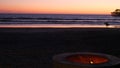Campfire pit in California USA. Camp fire on twilight ocean beach, bonfire flame, surfer and waves. Royalty Free Stock Photo