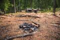 Campfire place in pine forest, with wooden shelters in the background