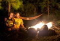 Campfire on a rocky beach with couple sitting Royalty Free Stock Photo