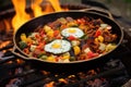 campfire skillet filled with breakfast foods on hot coals Royalty Free Stock Photo