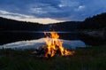 Campfire after sunset in the mountains next to a lake