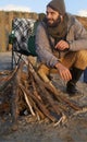 Campfire, wood and man by beach on vacation, adventure or holiday camping for travel. Nature, outdoor and young male