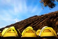 Campground in the mountains. Many yellow tents against the blue sky