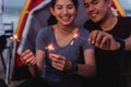 While camping, an Asian couple enjoys playing with sparklers fireworks Royalty Free Stock Photo