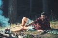 Camping and cooking food, vintage. Hipster with beard roast sausage on fire. Bearded man cook food on bonfire. Man in Royalty Free Stock Photo