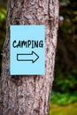 Camping directional sign handwritten on a blue paper mounted on a tree in the forest. Nature camp vacation Royalty Free Stock Photo