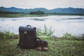 Camping equipment with a bag, backpack and leather shoes on the grass . mountain river nature background Royalty Free Stock Photo