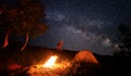Camping fire and tent under the amazing starry sky with lot of shining stars Royalty Free Stock Photo