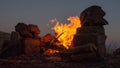 Camping fire in rock fireplace. The flames of the fire are curling around a small full moon in the sky