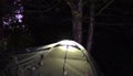 Camping in the forest at night with a green tent illuminated Royalty Free Stock Photo