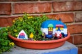 Camping gnome fairy garden in planter with minature camper and tent against blurred brick wall