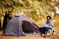 Camping holiday, tourist traveler woman in sweater and black hat ralaxing in camp tent in forest, rest vacation concept Royalty Free Stock Photo