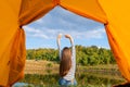 Camping on lake shore at sunset, view from inside tourist tent. Girl enjoy nature in front of tent