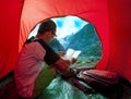 Camping man reading traveling guide book in camp tent against be