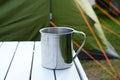 Camping metal mug on table with green tent in bcakground Royalty Free Stock Photo