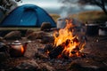 Camping in the mountains with a kettle and a tent on the background, Camp fire and tea pot are foreground and focused, there is a Royalty Free Stock Photo