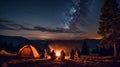 Camping in the mountains at night. Silhouettes of people sitting near bonfire and tent