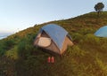 Camping on the mountains. A tourist tent on a green hill. A pink shoe in front of the tent.