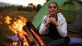 The girl is warming herself by the fire, smiling and looking to the camera Royalty Free Stock Photo