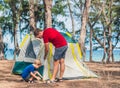 Camping people outdoor lifestyle tourists put up set up green grey camp site summer forest near lazur sea. Boy son helps