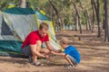 Camping people outdoor lifestyle tourists putting up setting up green grey campsite summer forest near lazur sea. Boy