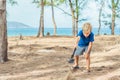 Camping people outdoor lifestyle tourists, summer forest near lazur sea. Blond boy play study survival techniques