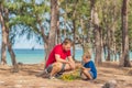 Camping people outdoor lifestyle tourists in summer forest near lazur sea. Blond boy son with father study survival