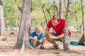 Camping people outdoor lifestyle tourists in summer forest near lazur sea. Blond boy son with father study survival