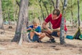 Camping people outdoor lifestyle tourists in summer forest near lazur sea. Blond boy son with father study survival