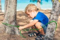 Camping people outdoor lifestyle tourists in summer forest near lazur sea. Blond serious boy in blue t-shirt study