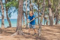 Camping people outdoor lifestyle tourists in summer forest near lazur sea. Blond serious boy in blue t-shirt study