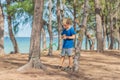 Camping people outdoor lifestyle tourists in summer forest near lazur sea. Blond serious boy in blue t-shirt study