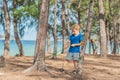 Camping people outdoor lifestyle tourists in summer forest near lazur sea. Blond serious boy in blue t-shirt study