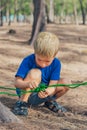 Camping people outdoor lifestyle tourists in summer forest near lazur sea. Blond serious boy in blue t-shirt study