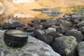 Camping pot with water in the background of mountains mirror reflection in the lake. Hiking motivational image