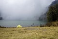 Camping site with tent and lake, misty foggy background Royalty Free Stock Photo