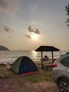 Camping with tent on the beach in the morning with golden sky. Tent and picnic table during sunrise with sunlight on a sandy beach Royalty Free Stock Photo