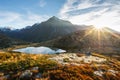 Camping with tent near high altitude lake on the Alps. Reflection of snowcapped mountain range and scenic colorful sky at sunset. Royalty Free Stock Photo