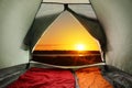 Camping tent with sleeping bags near river at sunset