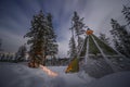 Camping tent in the snow forest with fire light in a cold winter in Finland